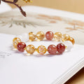 Yellow rutilated quartz and red flower-inclusion crystal butterfly bracelet on a warm background