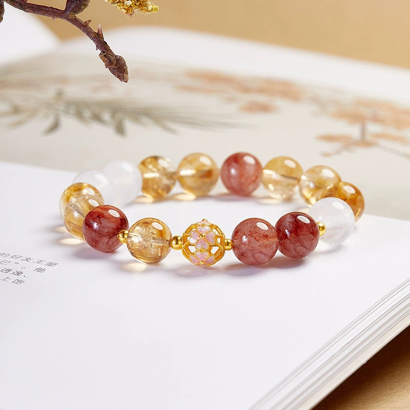 Yellow rutilated quartz and red flower-inclusion crystal butterfly bracelet on a warm background