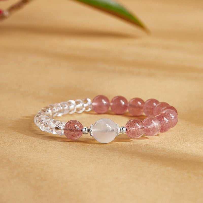 Strawberry crystal and clear quartz bracelet resting on a warm golden background