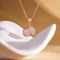 Pink mother-of-pearl milk tea cup necklace on a warm sculptural display