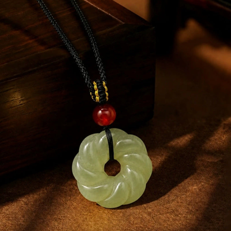 Nephrite jade twist ring pendant on a dark wood background