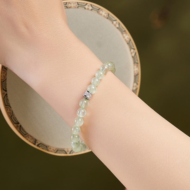 Prehnite bracelet worn on a model wrist beside a round fan