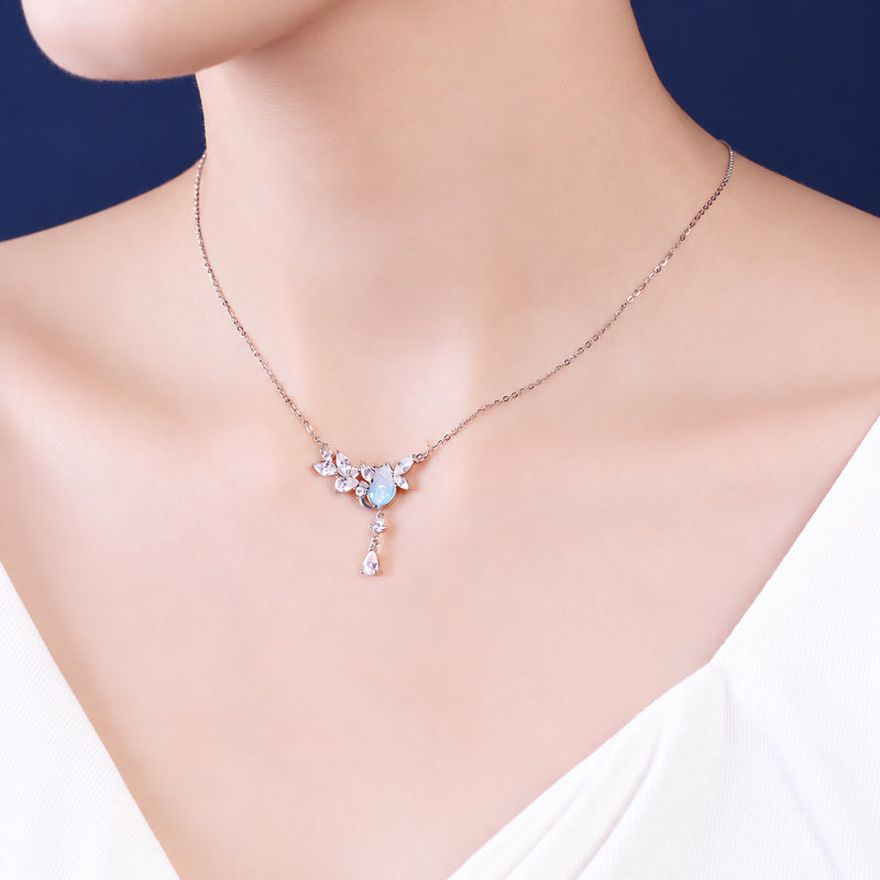 Model wearing delicate silver cat motif necklace with crystal drop