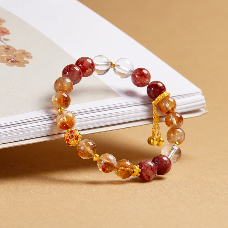 Golden and red crystal bracelet resting against a floral book