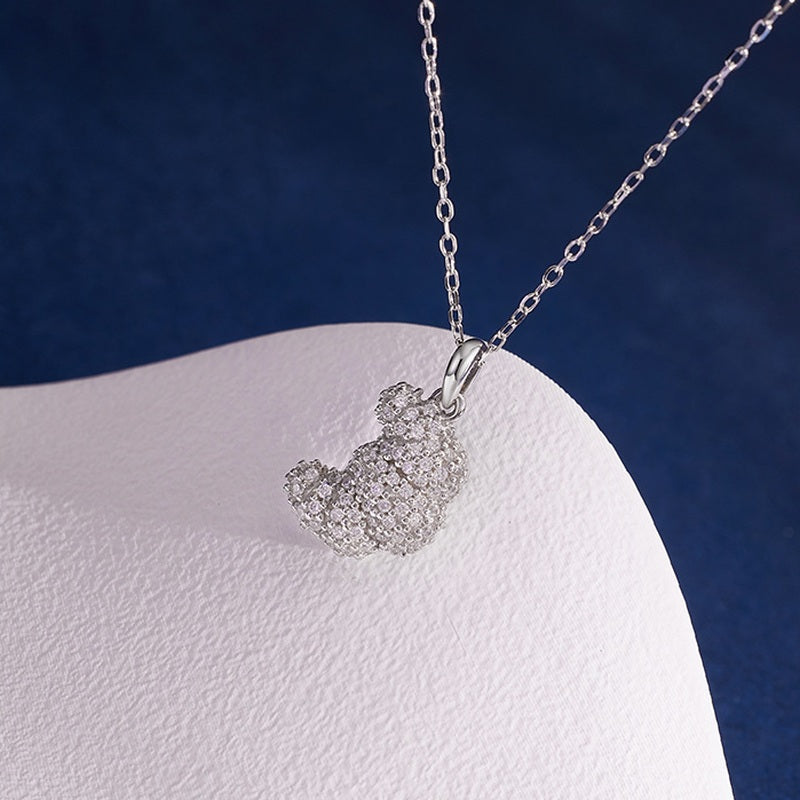 Pavé cubic zirconia croissant pendant close-up on sculpted backdrop