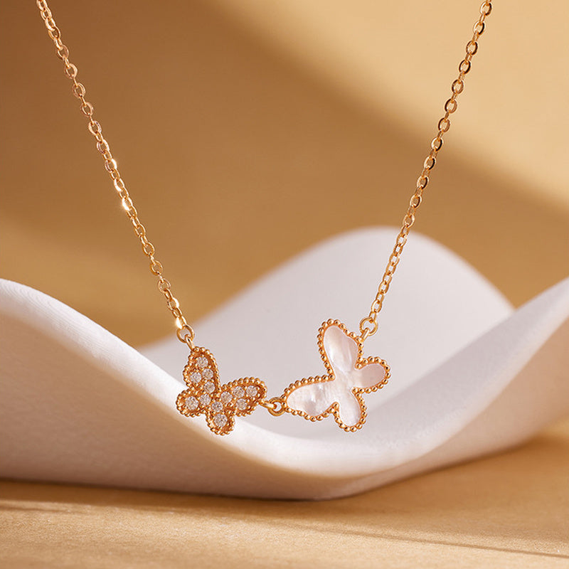 Double butterfly necklace displayed on sculptural white form