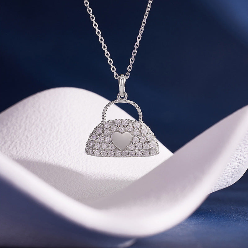 S925 silver handbag pendant displayed above soft white fabric