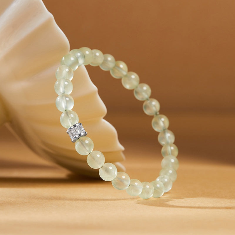 Single-loop prehnite bracelet leaning against a cream ceramic prop
