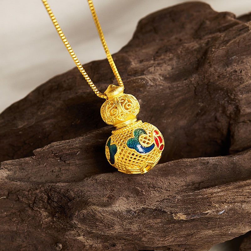 Blue green and red enamel gourd pendant resting on wood