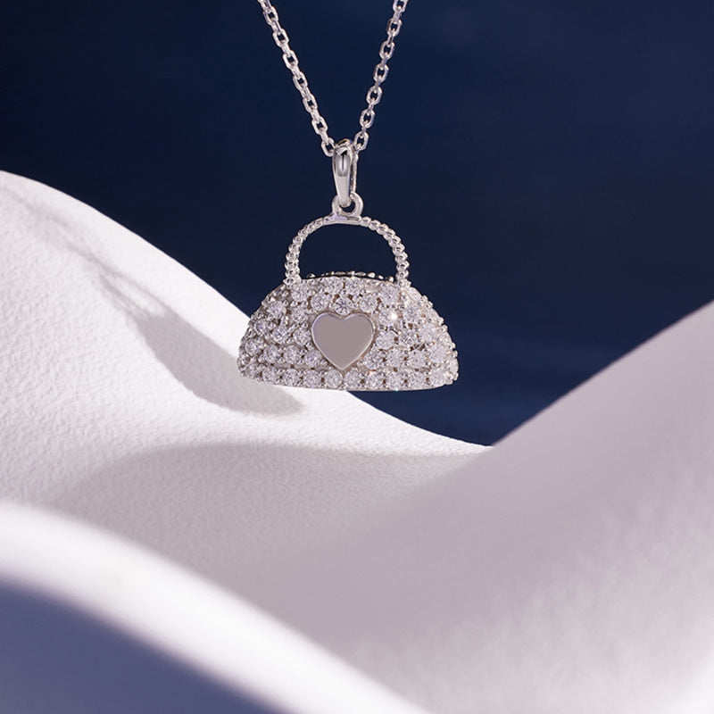 Stone paved heart handbag necklace against blue and white fabric