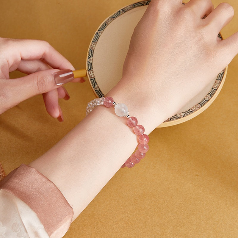 Original model wearing red strawberry crystal bracelet beside an embroidery hoop