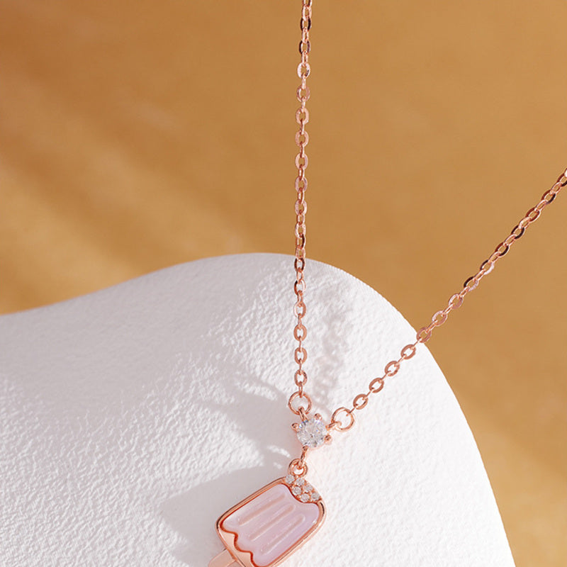 Rose gold color popsicle necklace resting on white display