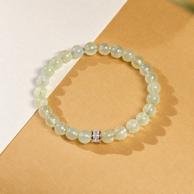 Overhead view of a prehnite bracelet on warm golden paper