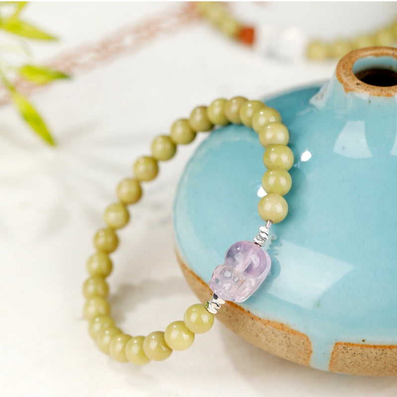 Green agate amethyst Pixiu bracelet displayed beside a blue ceramic vase