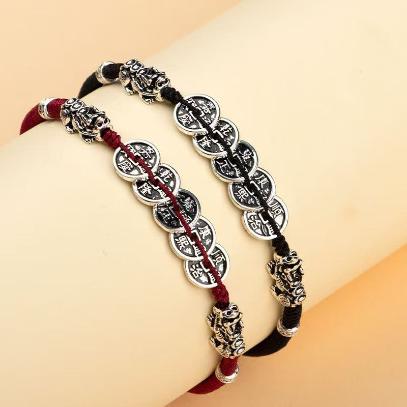 Red and black cord coin bracelets displayed together with silver and gold Pixiu