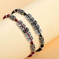 Red and black cord coin bracelets displayed together with silver and gold Pixiu