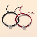 Matching red and black braided bracelets displayed together with oxidized silver guardian face charms.