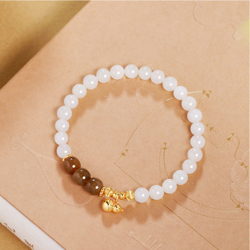 White jade gourd bracelet on a warm illustrated book
