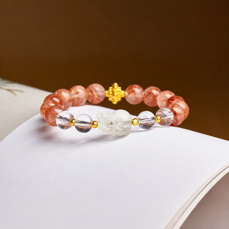 Lemon quartz Pixiu red inclusion quartz bracelet on a book with brown background