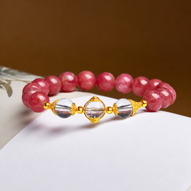 Clear quartz Wealth Deity and pink rhodonite bracelet on a warm brown and paper background