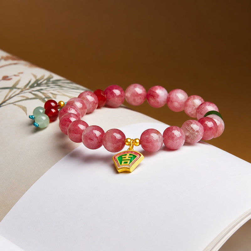 Rhodonite bracelet with Ji charm, red agate and nephrite jade on a warm book background