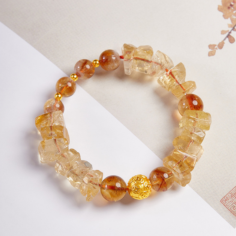 999 silver coin and Yellow Tower Quartz bracelet centered on a patterned paper background