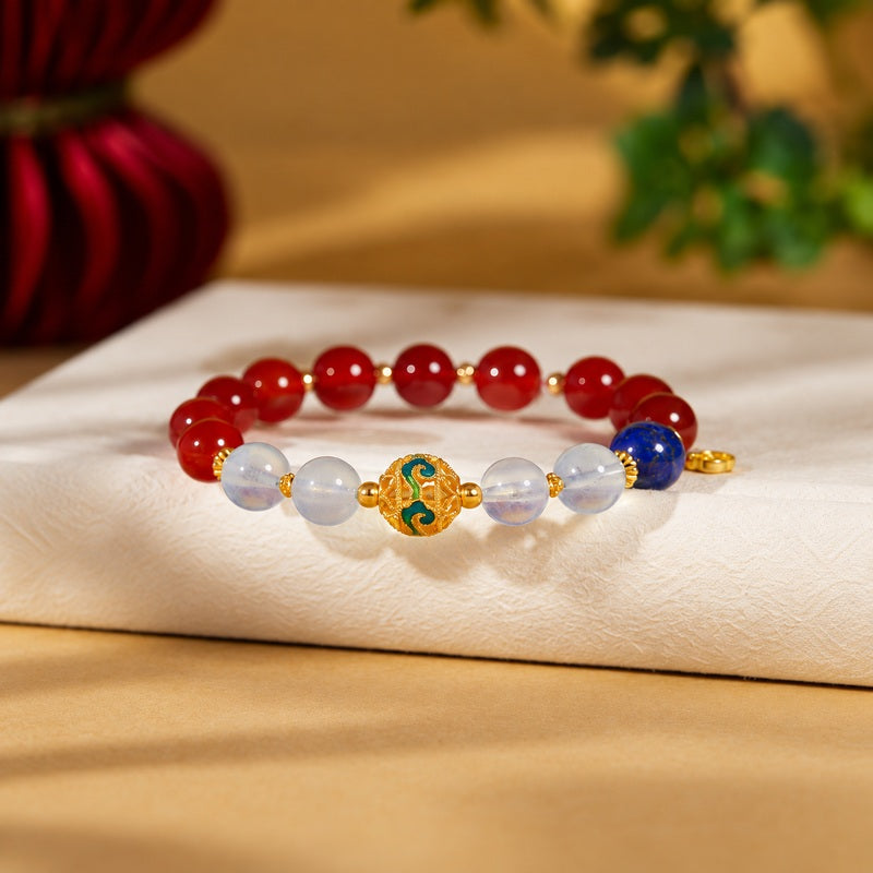 Cold-enamel red agate bracelet with filled aquamarine and lapis lazuli on a warm fabric background