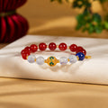 Cold-enamel red agate bracelet with filled aquamarine and lapis lazuli on a warm fabric background