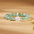 Green strawberry crystal and blue moonstone bracelet on a warm golden surface