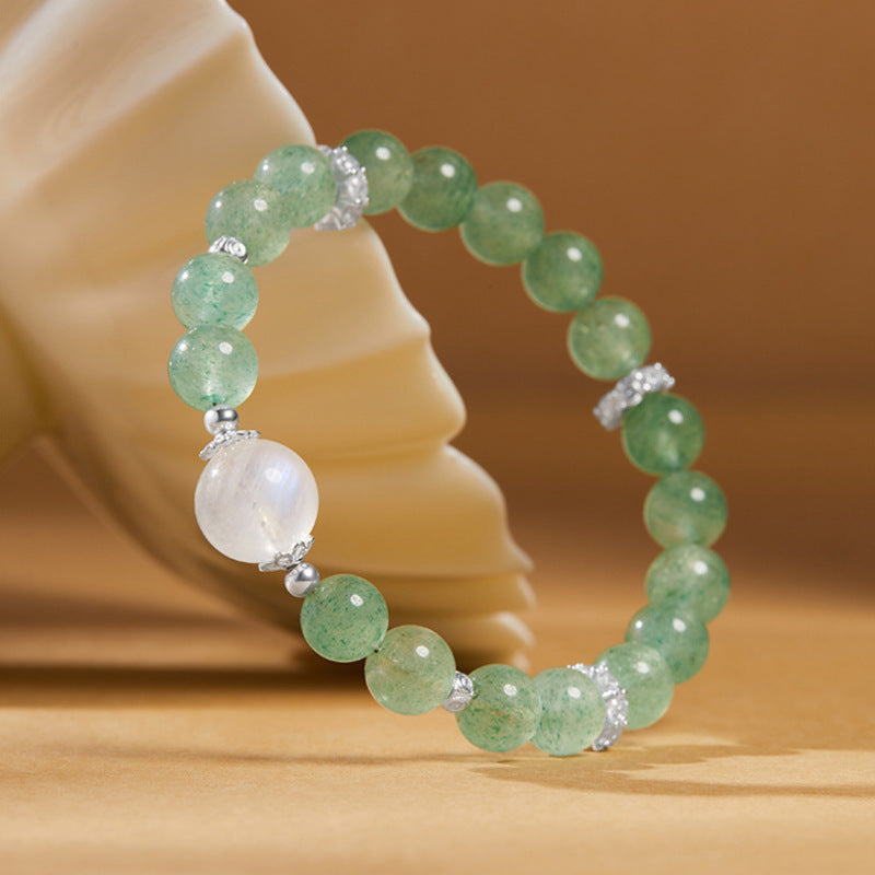 Green beaded moonstone bracelet leaning against a cream ceramic prop