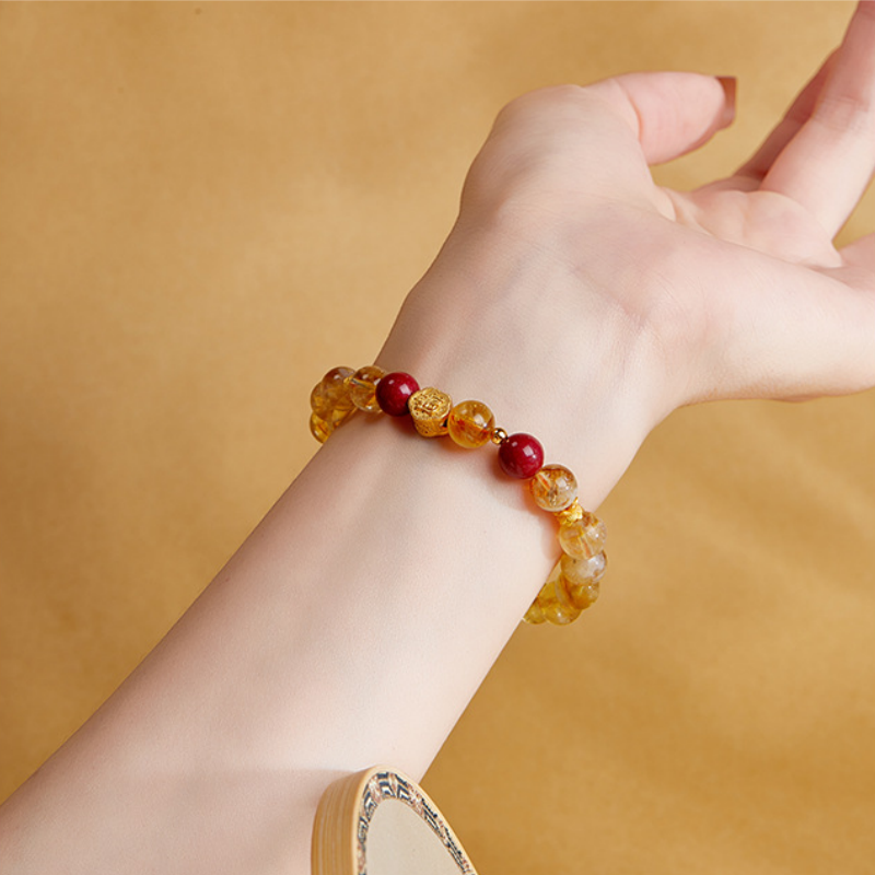 Yellow quartz and red bead bracelet worn on a woman's wrist