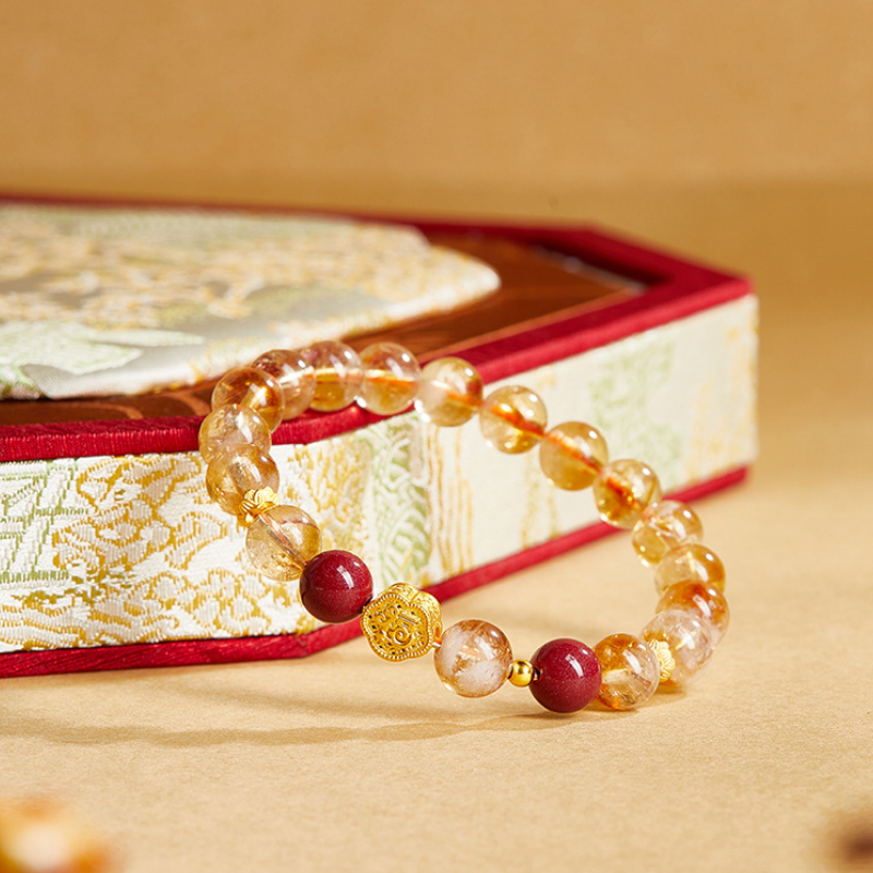 Good fortune yellow quartz bracelet resting beside an embroidered box