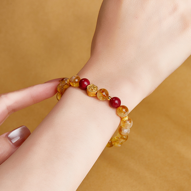 Close view of yellow quartz bracelet and good fortune charm on wrist