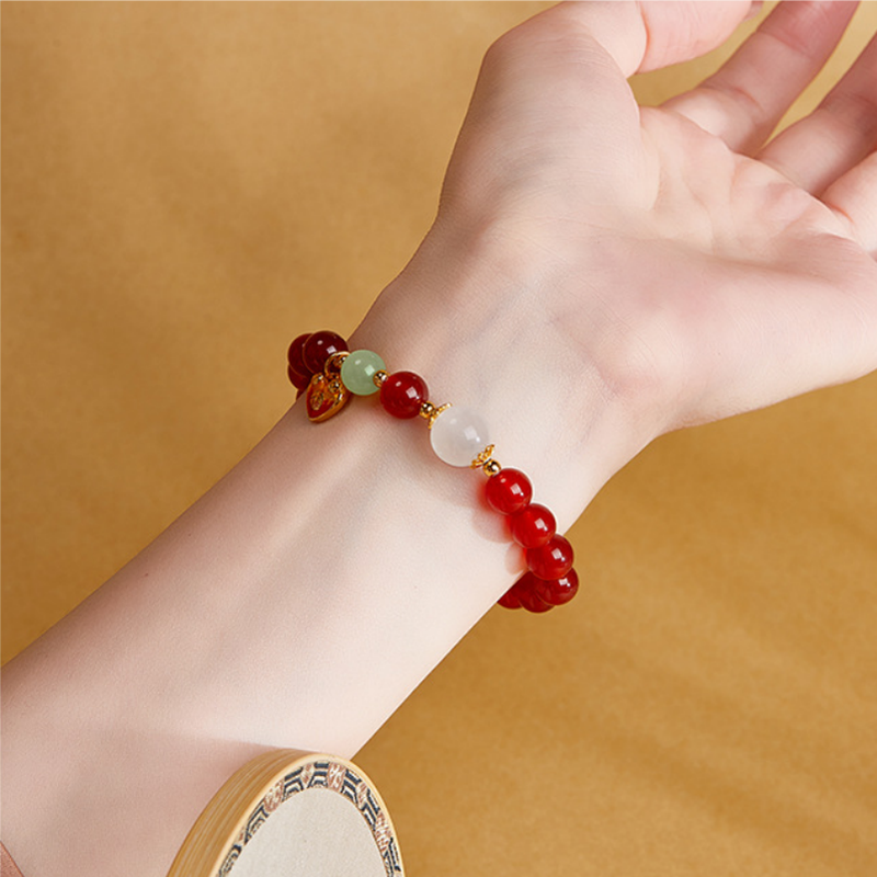 Heart charm bracelet showing red agate and moonstone on an upturned wrist