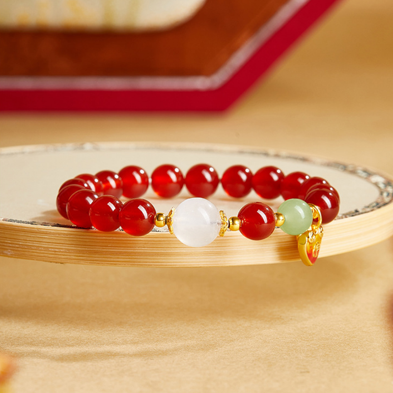 Red agate heart bracelet with jade and moonstone on a golden tray