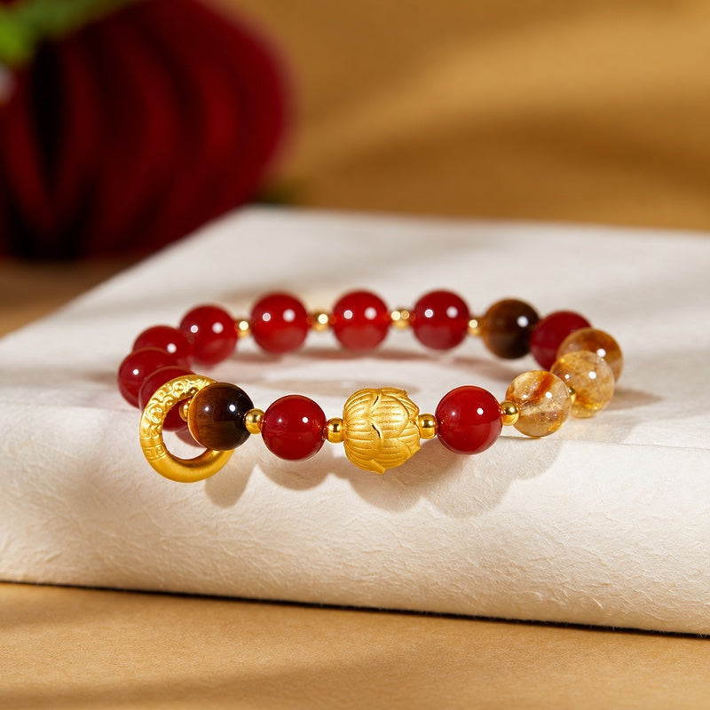 Red agate lotus bracelet with golden details on an ivory prop