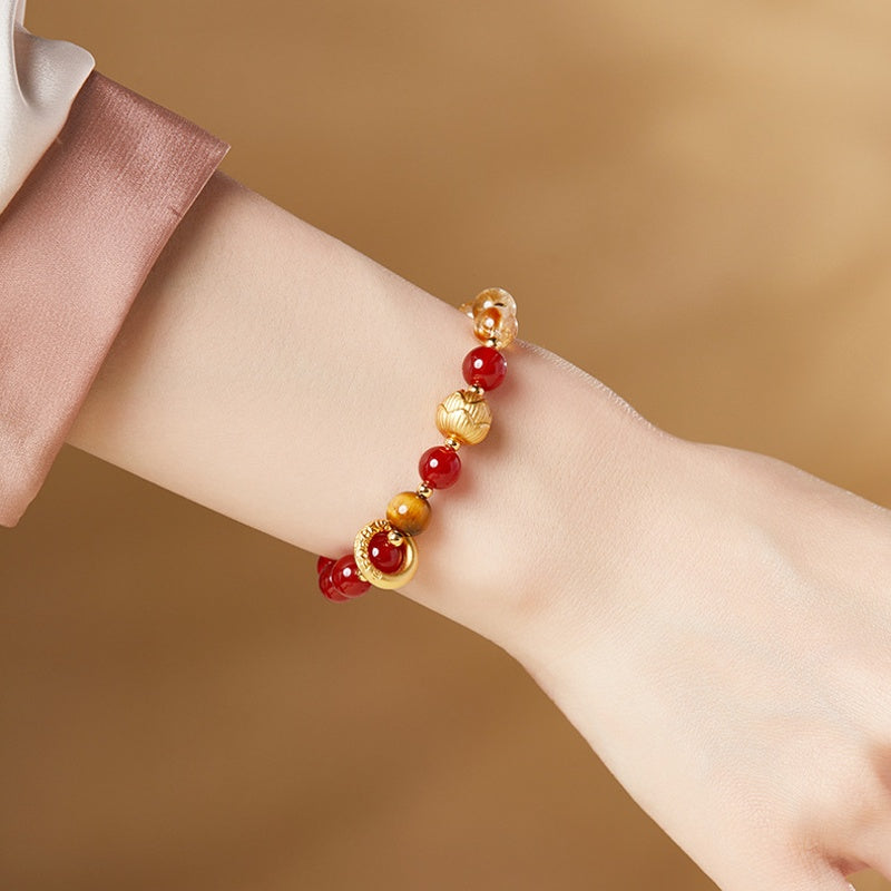 Lotus and red agate bracelet shown on wrist against warm background