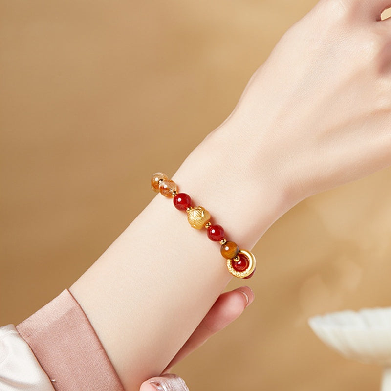 Red agate lotus bracelet worn on wrist with a pink cuff