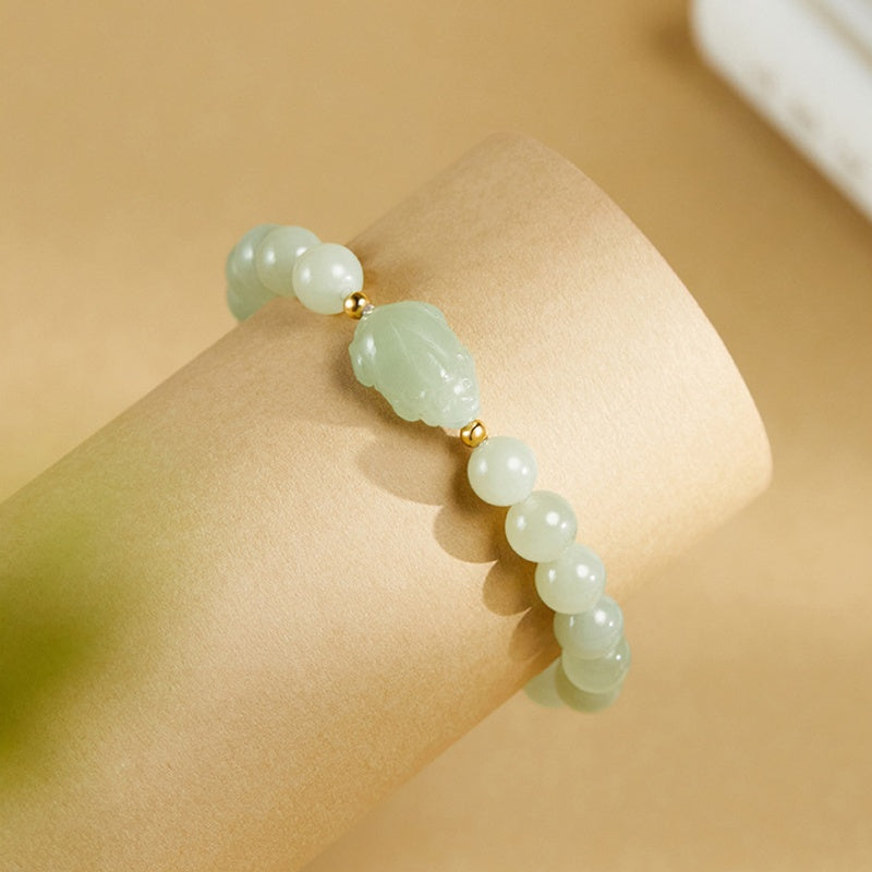 Carved nephrite jade toad bracelet on a display roll