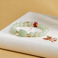 Nephrite jade toad bracelet with red Zijinsha bead on a cream book