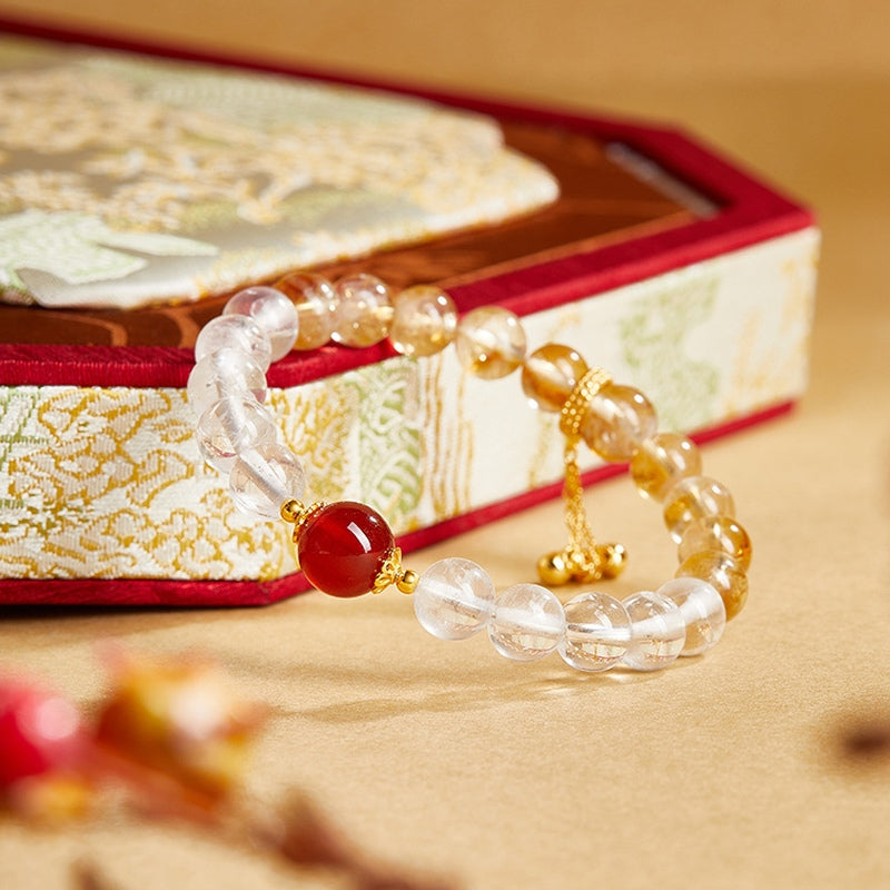 Red agate bracelet resting beside a brocade prop