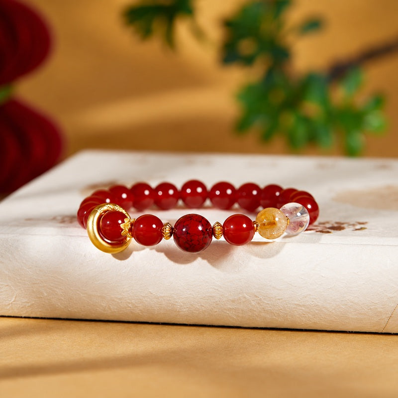 Red agate silver circle bracelet resting on a warm cream book