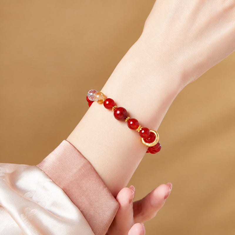 Red agate silver circle bracelet worn beside a pink satin cuff