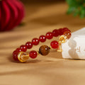 Red agate lotus seedpod bracelet resting against an ivory fabric prop