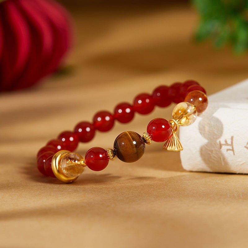 Red agate lotus seedpod bracelet resting against an ivory fabric prop