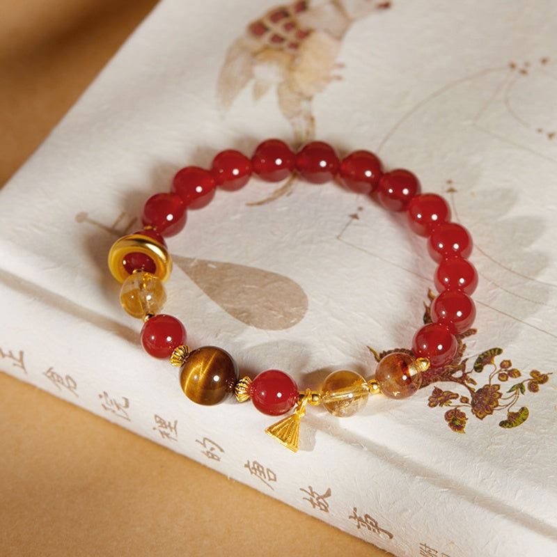 Overhead view of red agate lotus bracelet on patterned ivory fabric