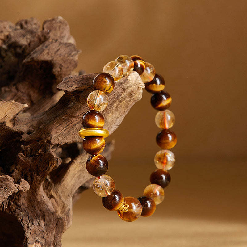 Tiger's eye and yellow quartz bracelet displayed on natural driftwood