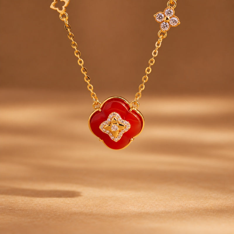 Red agate four-leaf clover necklace against a warm golden background