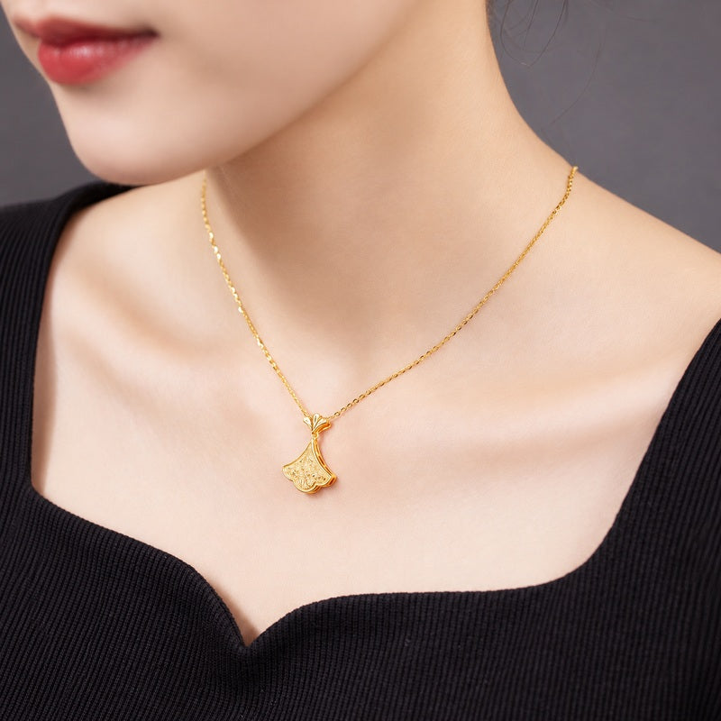 Supplier model wearing the gold-tone ginkgo necklace with a black neckline