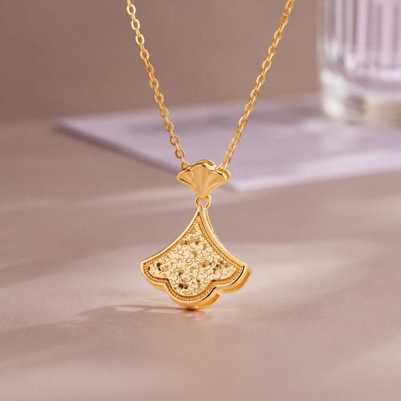 Ginkgo necklace resting on a taupe surface with natural soft shadows